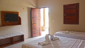 Habitación de hotel con dos camas, un banco, un televisor y puertas de madera.
