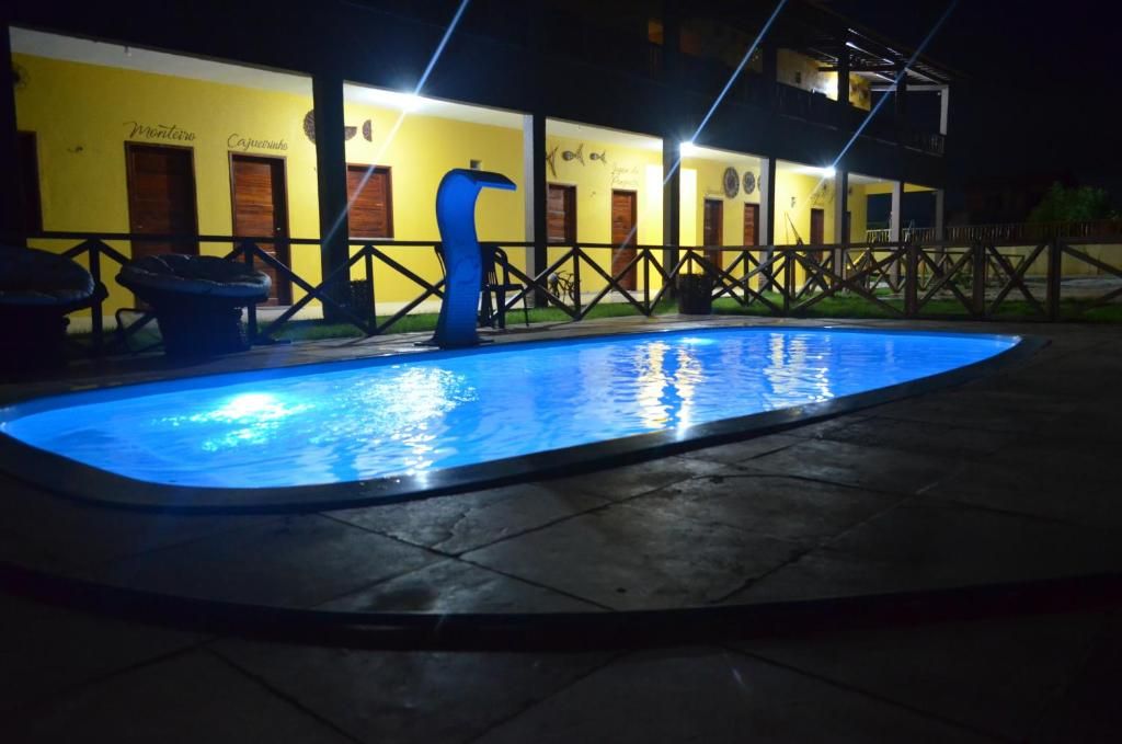 Una piscina con luz azul, un edificio amarillo con puertas y una valla.