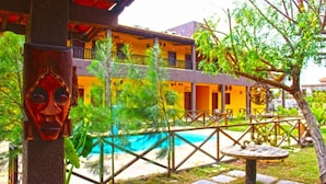 Un edificio de dos plantas con balcones, piscina y jardín tropical.