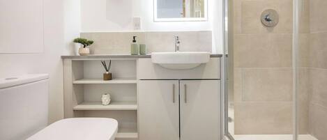 Un baño moderno con inodoro, lavamanos y ducha.
