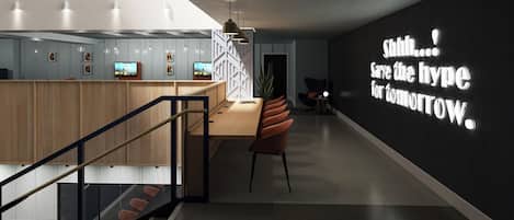 A modern interior with a staircase, a reception desk, and a wall with a motivational quote.