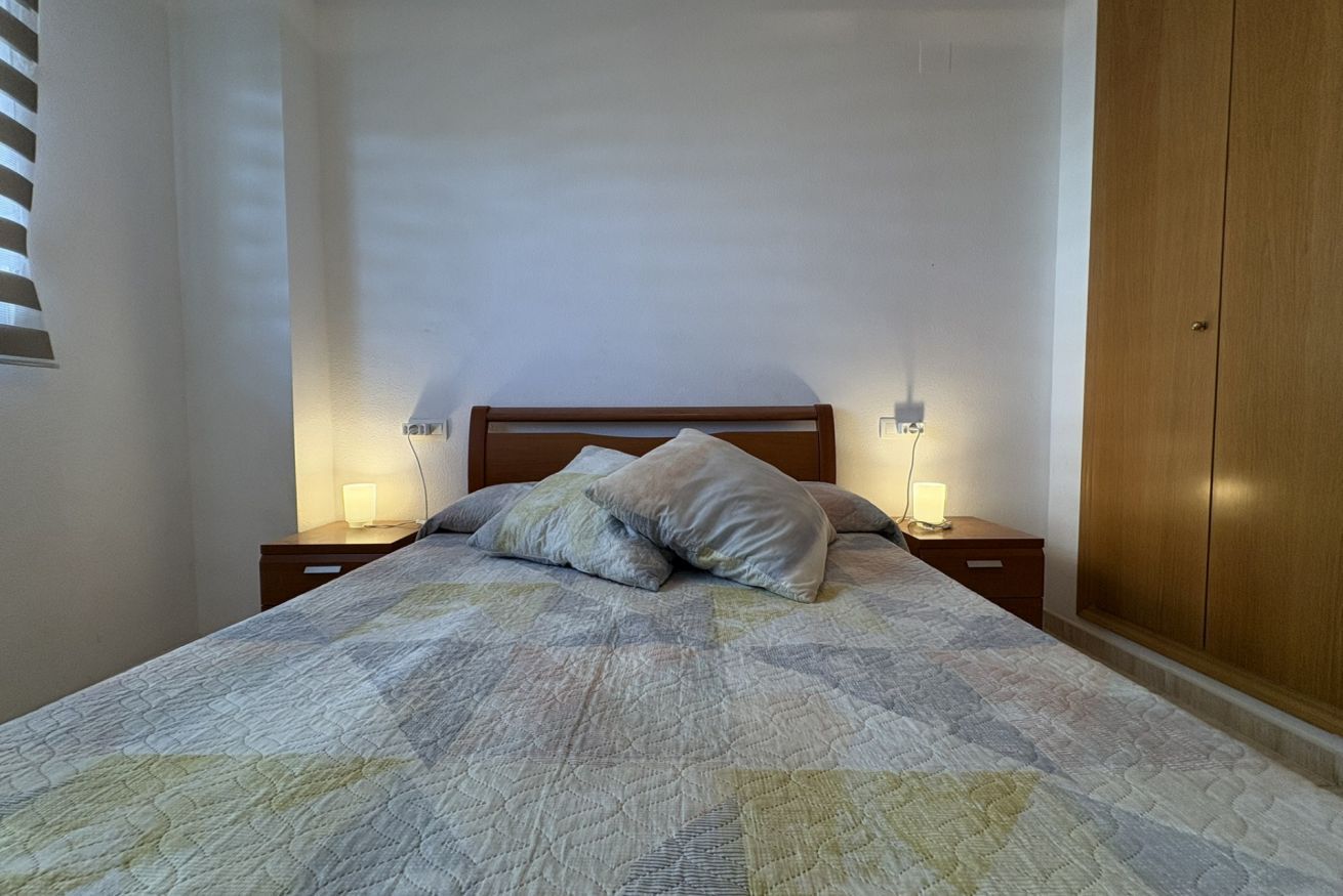 Ein Schlafzimmer mit einem Bett, zwei Nachttischlampen, einem hölzernen Kopfteil und einem Kleiderschrank.