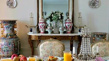 A dining table set with various dishes, a mirror, decorative vases, and wall sconces.