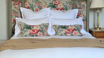 A bed with floral headboard, white pillows, and a checkered bench.