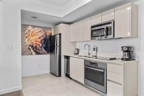 A modern kitchen with stainless steel appliances, a microwave, a coffee maker, and a dishwasher. - Stylish Modern 1BR, Bay View Balcony, Resort Style (Hallandale Beach)