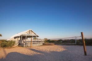 A beach house with a deck, a volleyball net, and a sandy beach. - BLOCK Blue Ridge Village 1br (Banner Elk)