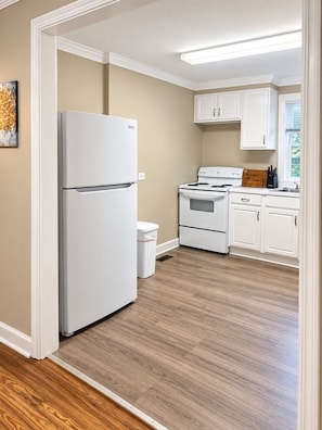 A kitchen with white cabinetry, a refrigerator, an oven, and a stove.