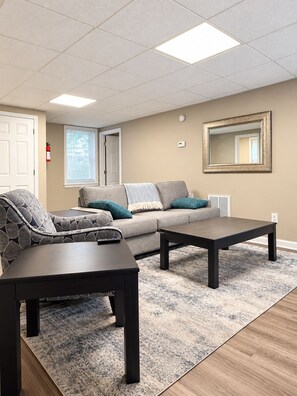 A furnished living room with a sofa, two coffee tables, a rug, and a large mirror on the wall.