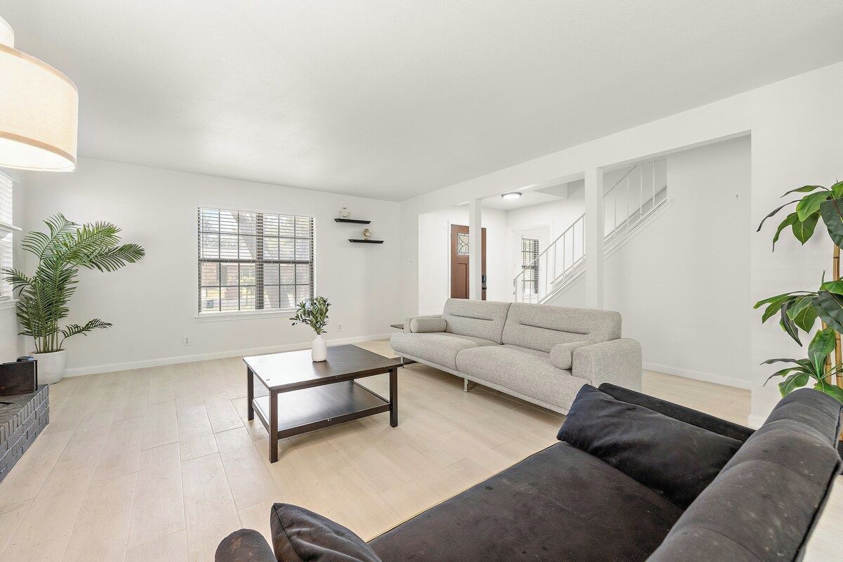 A spacious living room with a sofa, a coffee table, and a staircase leading to another level.