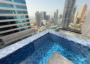 A rooftop pool with a cityscape view, modern high-rise buildings, and a marina. - Stayshort - Chic 1 Bedroom Unit in Dubai Marina That Sleeps 4 (Dubai)
