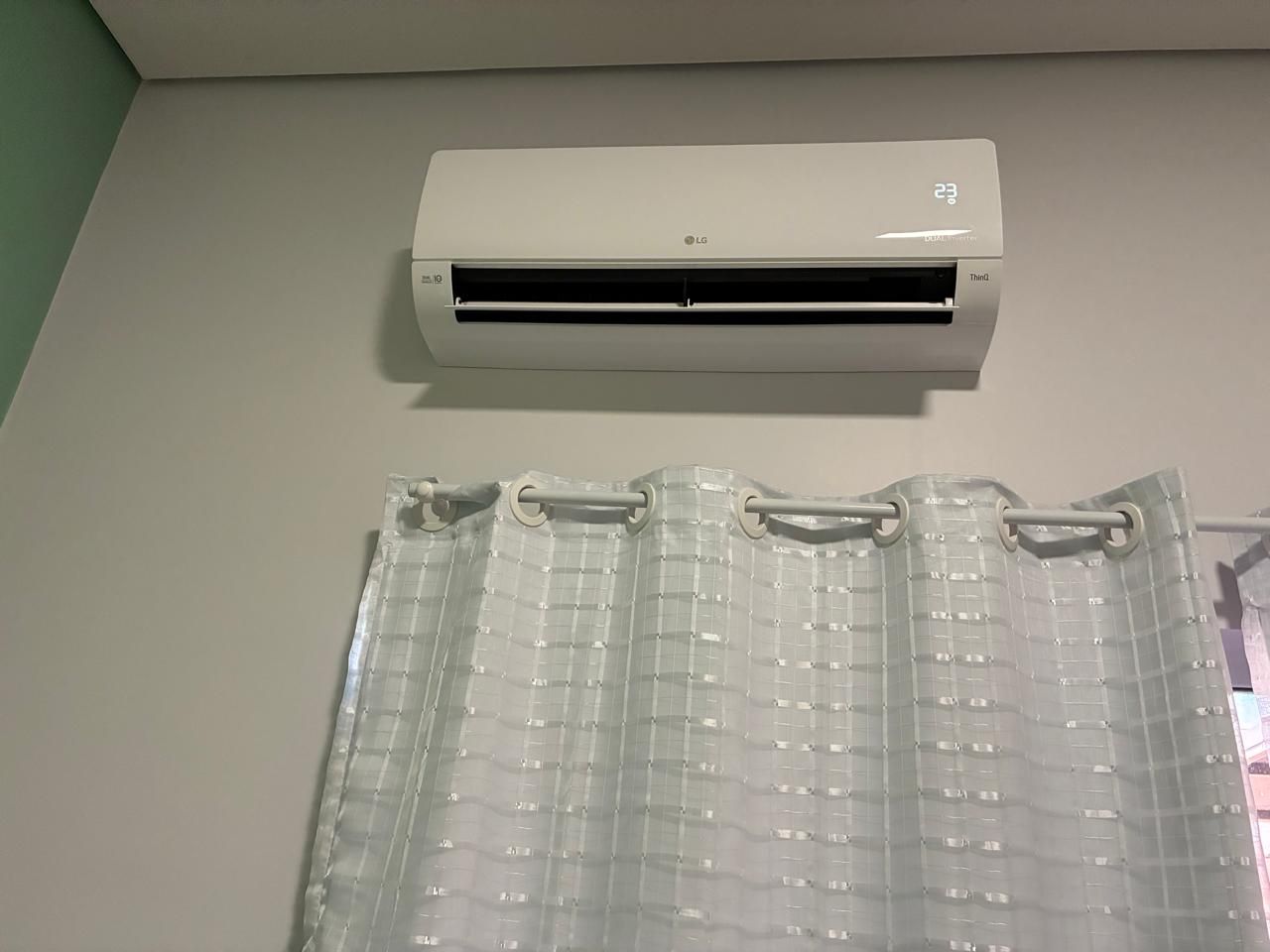 Un equipo de aire acondicionado blanco montado en una pared, con una cortina de plástico transparente debajo.