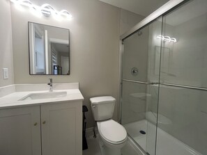 A modern bathroom with a glass shower enclosure, a white toilet, and a vanity with a mirror. - Room +Private Bath in New Windsor House (Windsor)