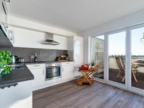 A modern kitchen with a built-in oven and a dining area with a view. - Holiday Apartment With 1 Bedroom (Kappeln)