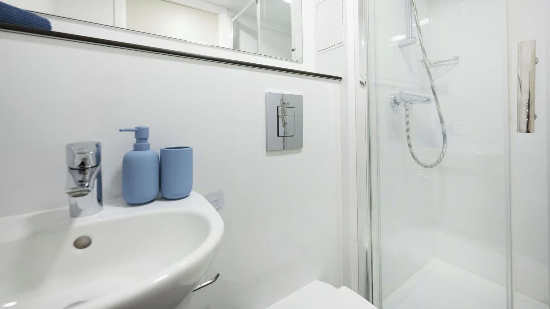 A modern bathroom with a white sink, a glass shower enclosure, and a mirror above the sink.