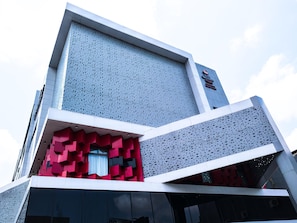 Un edificio moderno con fachada geométrica, un letrero destacado y una pared con diseño.