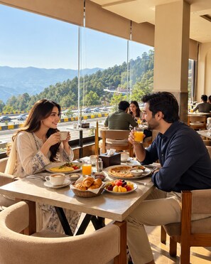 Un comedor con una mesa preparada para el desayuno, que incluye cruasanes, fruta y bebidas.