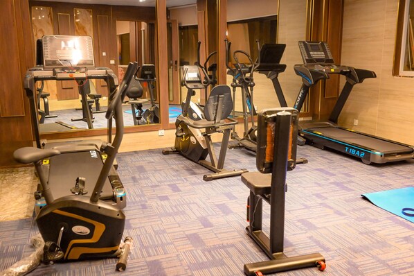 Un gimnasio con diversos equipos de ejercicio, incluyendo cintas de correr, bicicletas estáticas y máquinas de pesas.