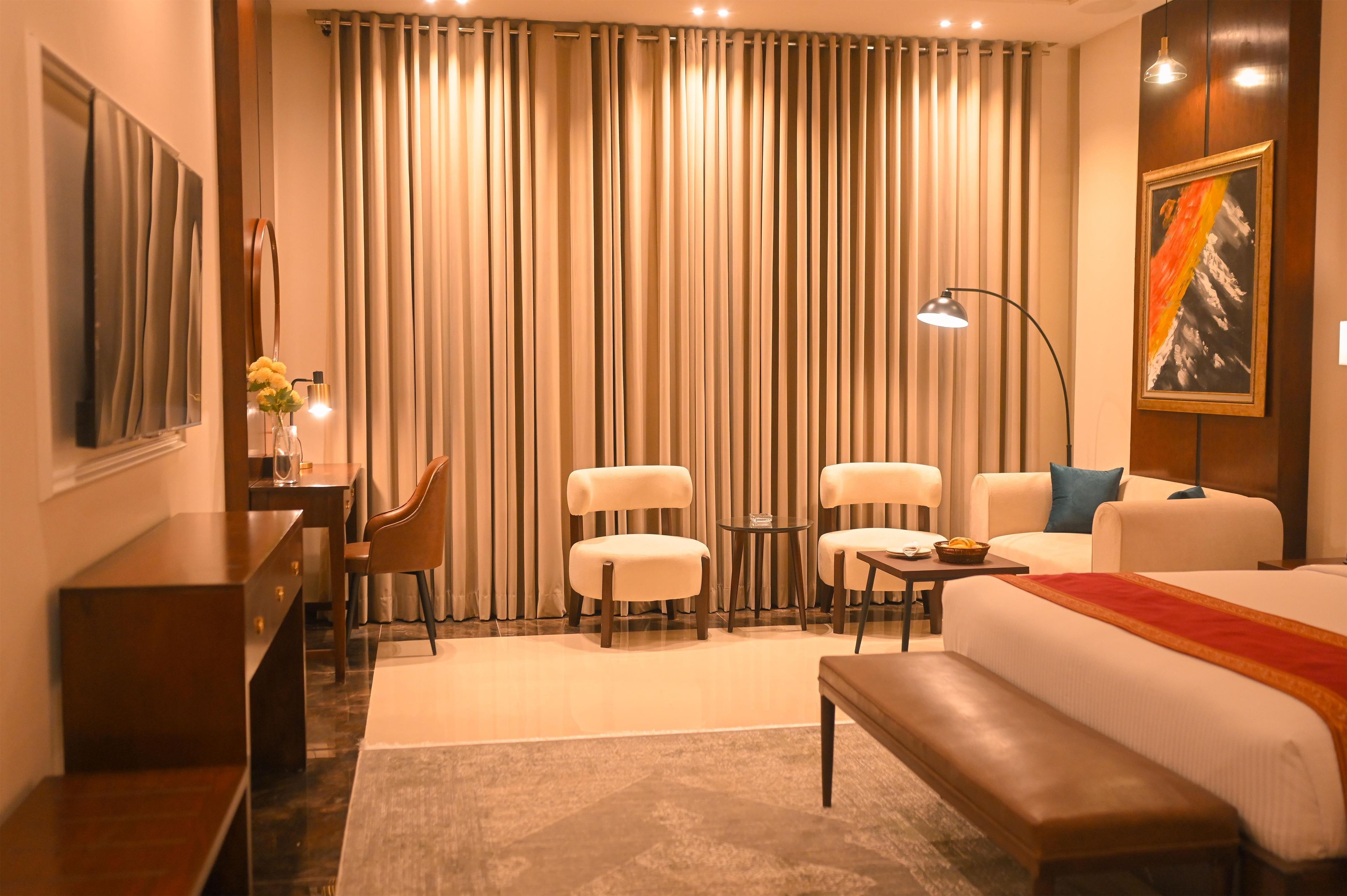 Una habitación de hotel con una cama, dos sillones, un sofá, un escritorio y una lámpara.