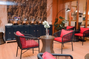 A room with dark blue furniture, red cushions, a glass table with a vase, and decorative globes on a cabinet.