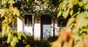 A building with a dark door, a light wall, and a small garden area with flowers and plants. - Hahndorf On Main, Bw Signature Collection (Hahndorf)