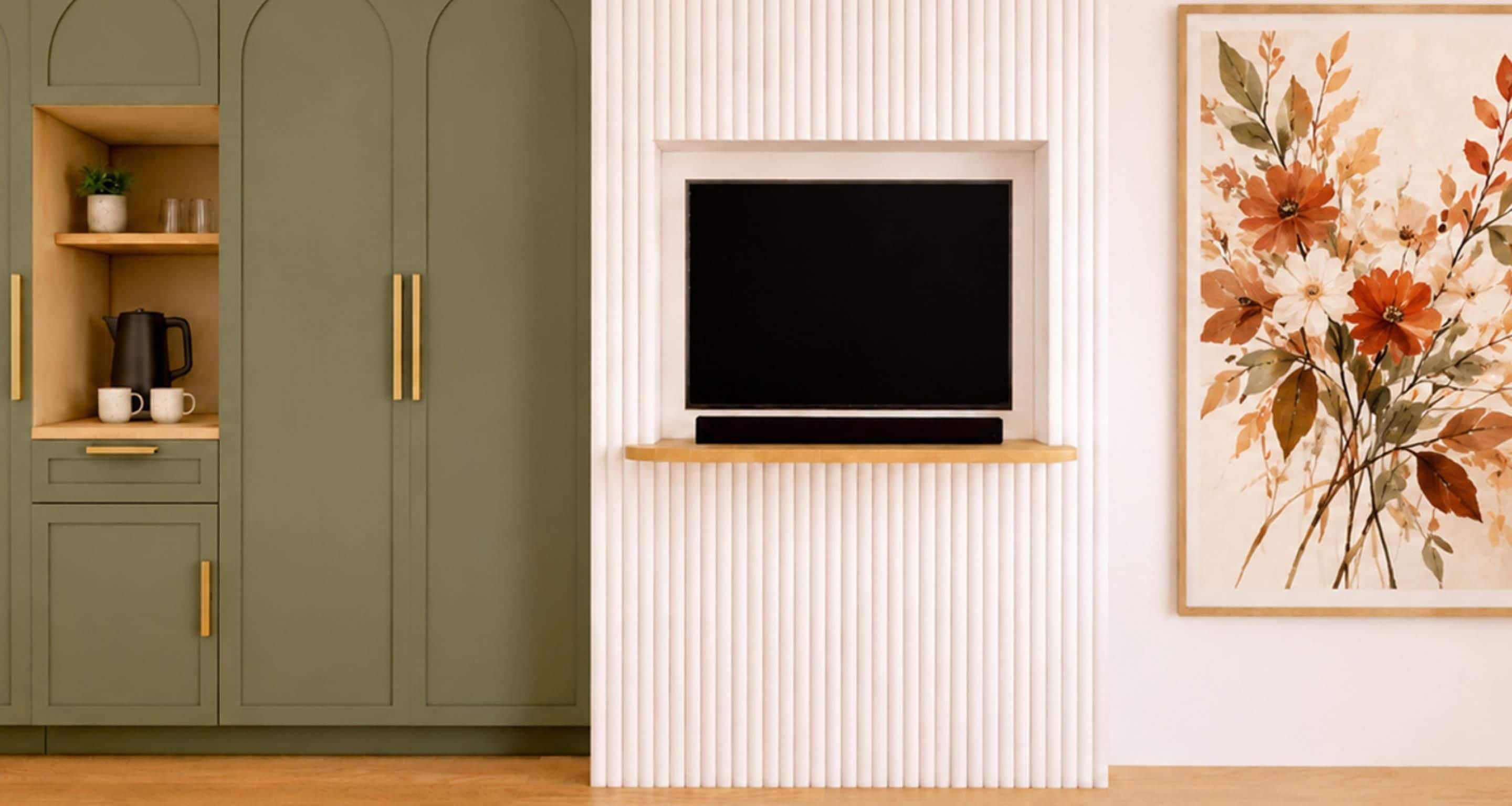 Ein Zimmer mit einem an der weißen Wand befestigten Fernseher, einem grünen Schrank mit Ablagefläche und einem gerahmten Blumenbild.