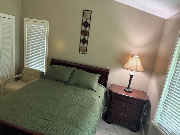 A bedroom with a bed, a nightstand, a chair, and a wall decoration.