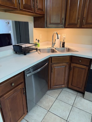 A kitchen with wooden cabinets, a stainless steel sink, and a dishwasher.
