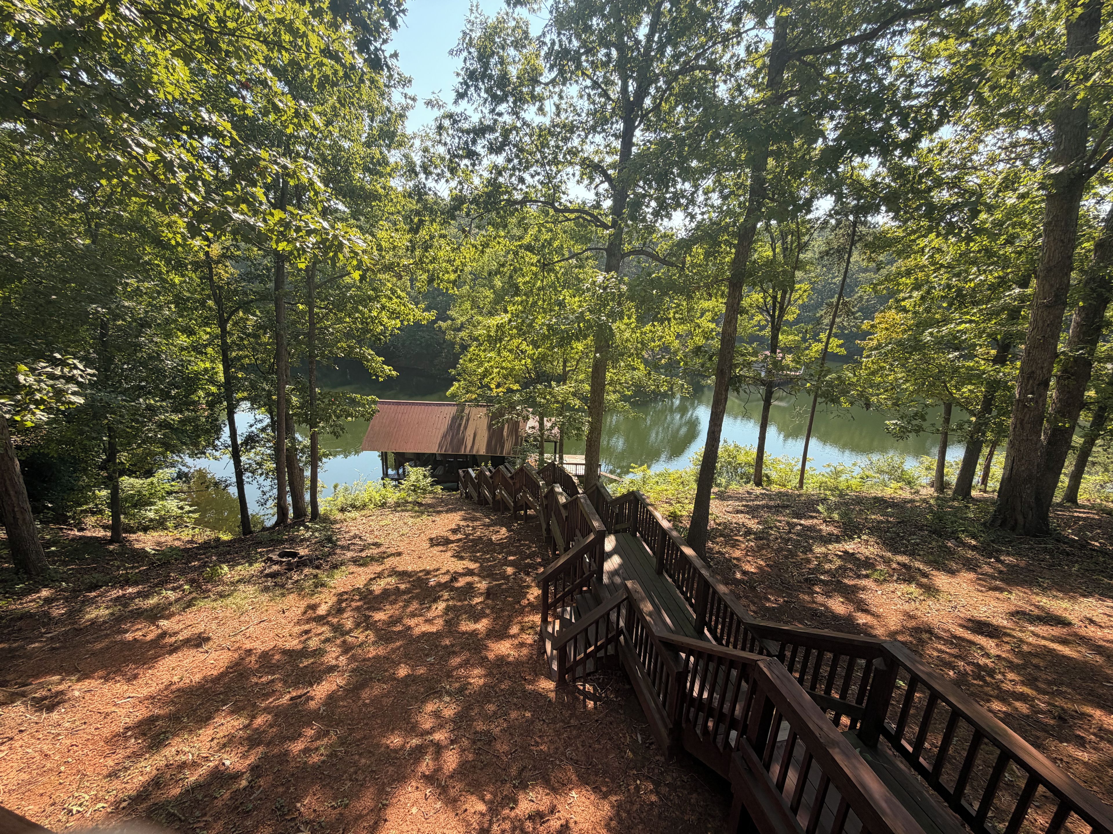 A wooden deck leading to a rustic cabin by a lake surrounded by trees.