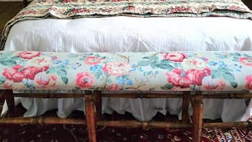 A bed with a floral bedspread, a matching bench, and a patterned rug.