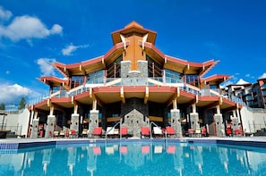 A multi-story hotel with a pool in front, featuring balconies and outdoor seating. - Copper Sky Retreat (Central Okanagan)
