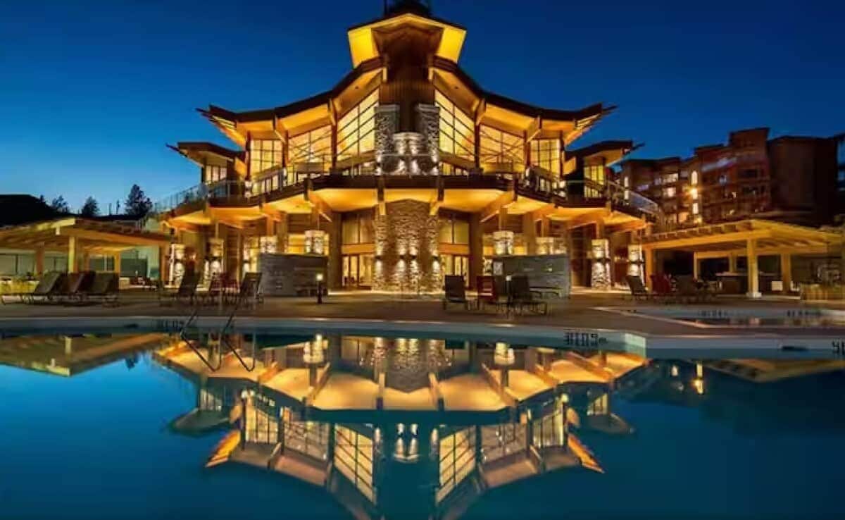 Un hôtel à plusieurs étages avec une piscine à l’avant, doté d’un atrium central et de balcons.
