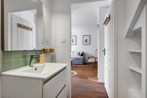 A modern bathroom with a white sink, green-tiled backsplash, and a wooden door. - Holiday Home 'Porteau rouge' gîte de la Presqu'île (L'Aiguillon-la-Presqu'île)