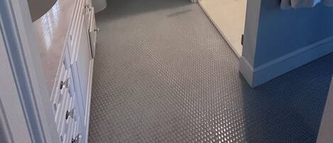 A bathroom with a toilet, sink, shower, and a framed picture on the wall.