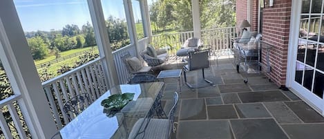A covered patio with a table and chairs, a ceiling fan, and a view of the landscape.