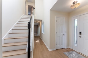 A staircase with a handrail leading to a landing, a door with a peephole, and a light fixture on the ceiling. - Bradley Creek Retreat 5 min to Wrightsville Beach (Wilmington)