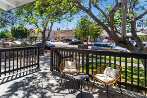 A covered outdoor area with two wicker chairs and a small table, overlooking a street with parked cars and buildings. - Uptown San Diego Charm with 2BR + Patio & Parking (San Diego)