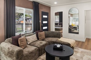A living room with a sectional sofa, a round coffee table, and a large mirror. - Uptown San Diego Charm with 2BR + Patio & Parking (San Diego)