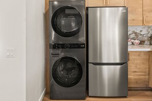 A compact kitchen with a stainless steel refrigerator and a front-loading washer. - Uptown San Diego Charm with 2BR + Patio & Parking (San Diego)