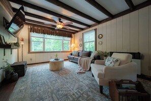 A cozy living room with a fireplace, a sofa, a coffee table, and a ceiling fan.