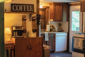 Una cocina con armarios de madera, una estación de café, un lavavajillas y un horno.
