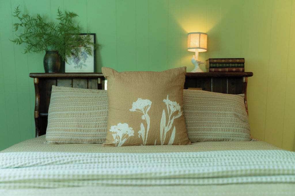 Un lit avec une couvre-lit à motifs et deux oreillers ornés de motifs floraux.