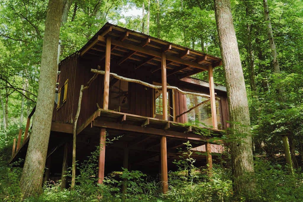 A wooden cabin with a balcony, surrounded by trees.