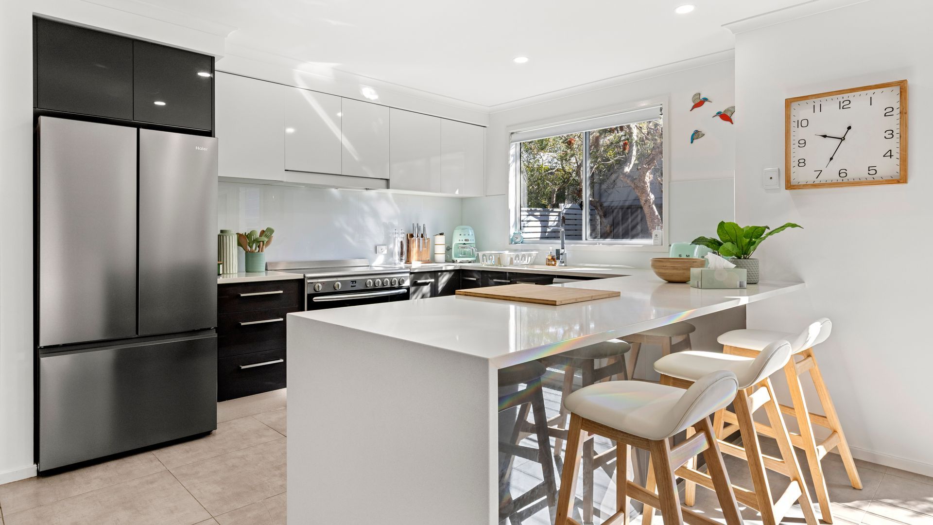Una cocina moderna con una isla grande, electrodomésticos de acero inoxidable y un ventanal que proporciona luz natural.
