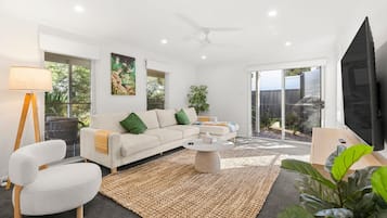A modern living room with a sofa, coffee table, and a flat-screen TV.