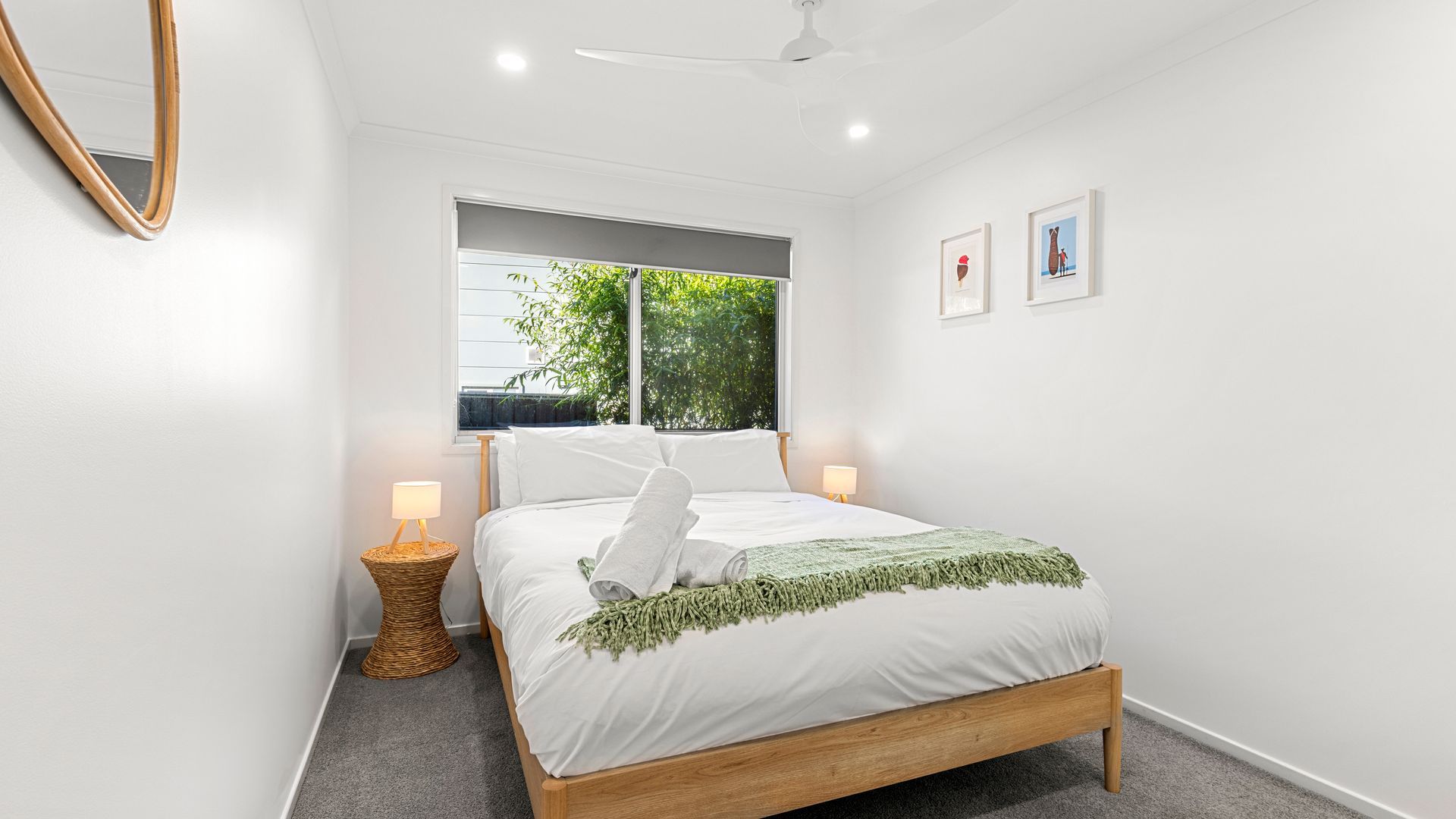 A bedroom with a bed, a window, a ceiling fan, and wall-mounted artwork.
