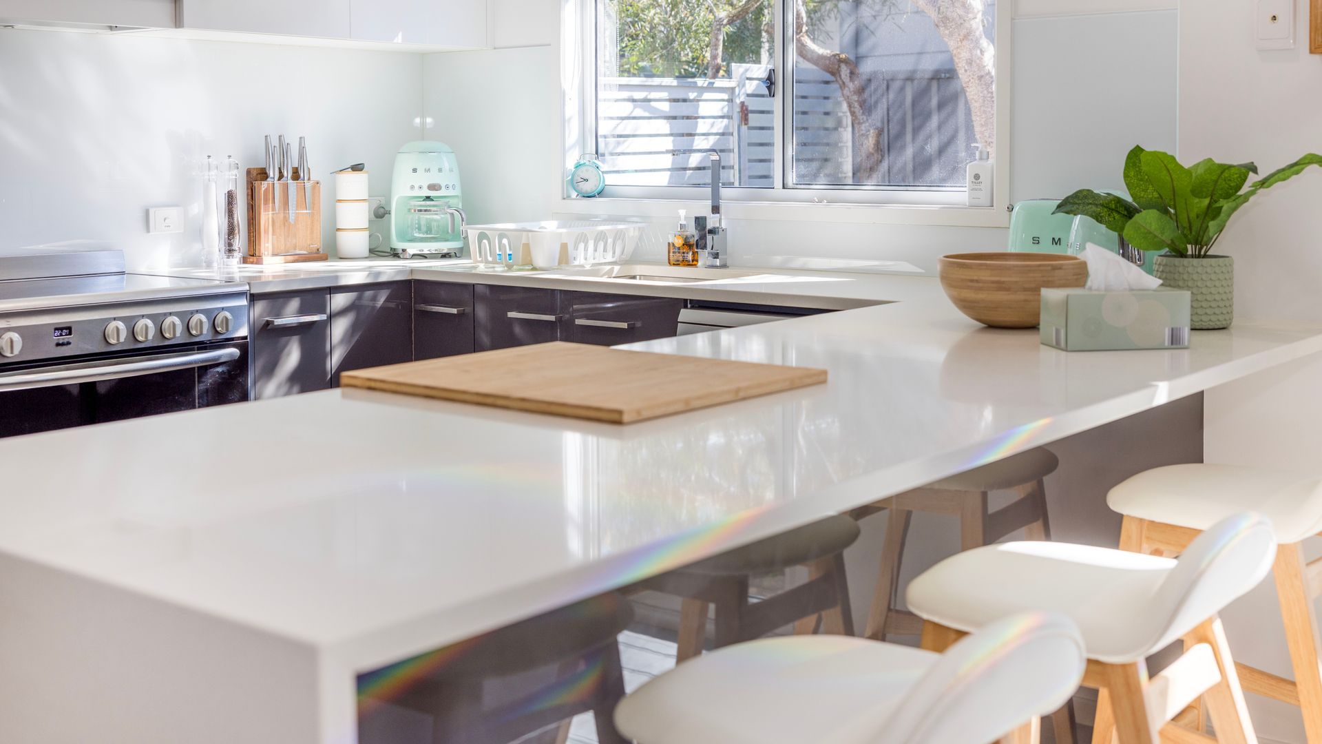Una cocina moderna con una isla central, electrodomésticos de acero inoxidable y vistas al exterior.