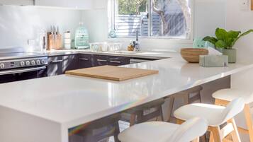 Una cocina moderna con una isla central, electrodomésticos de acero inoxidable y vistas al exterior.