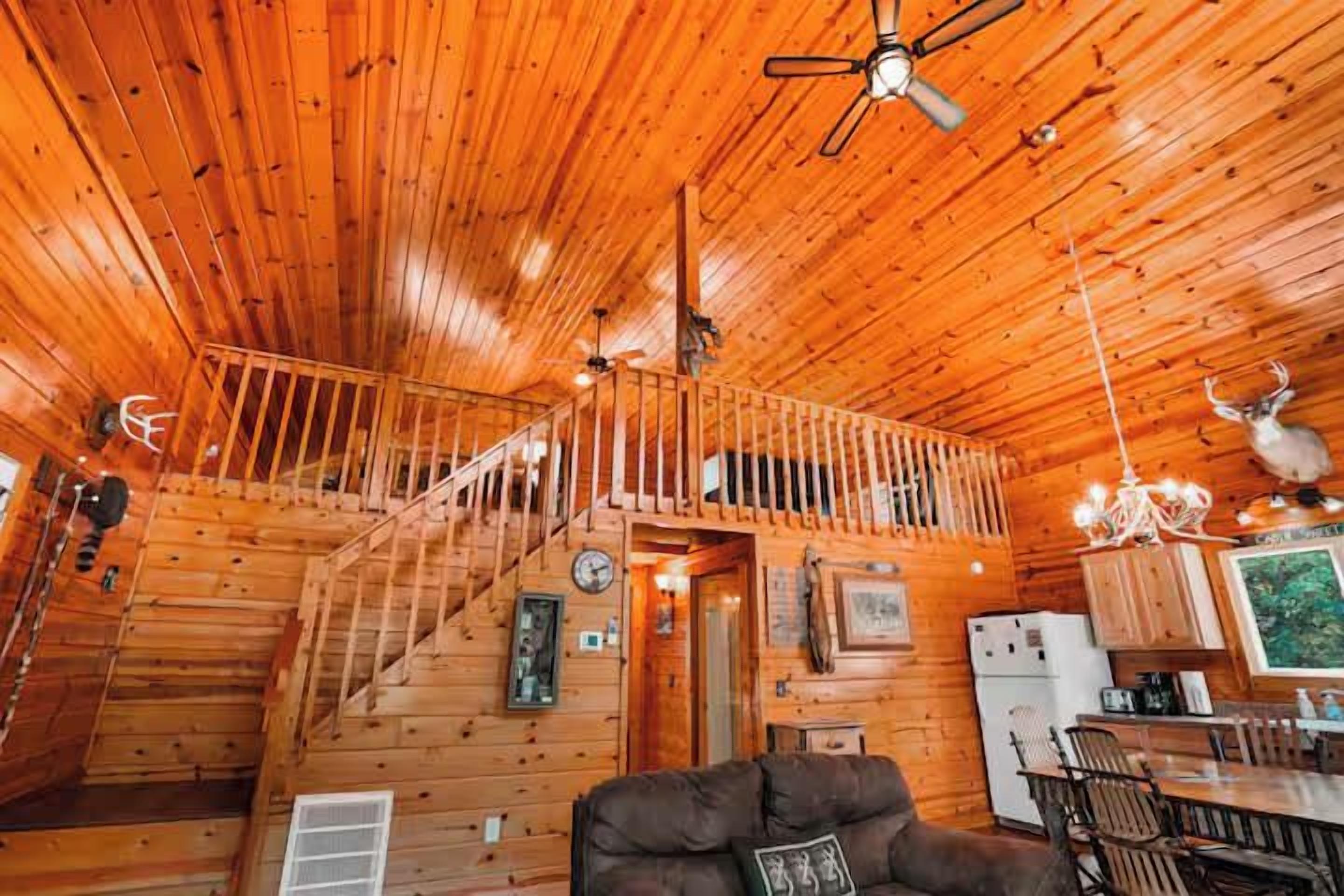 Interior de una cabaña de madera con escalera, comedor y sala de estar.