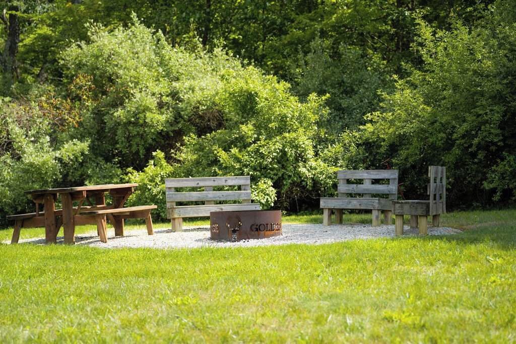 A picnic area with wooden benches and a picnic table surrounded by lush greenery.