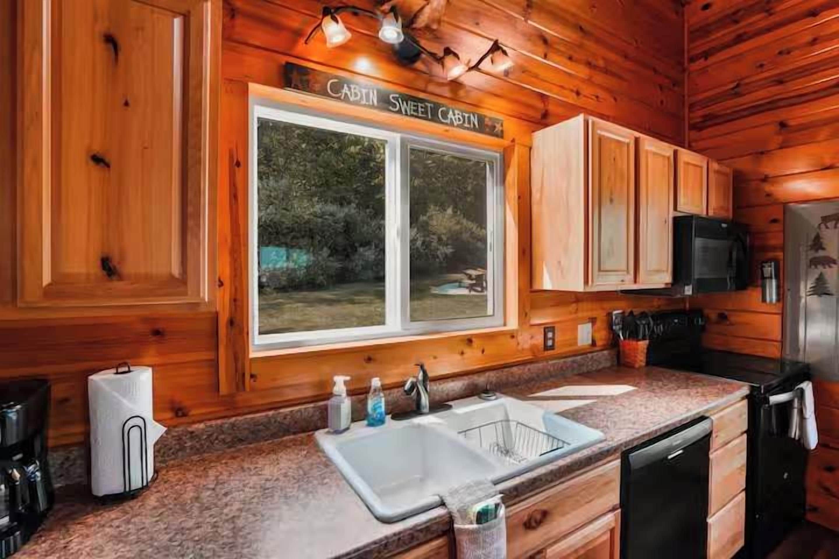 Una cocina tipo cabaña con paredes de madera, un lavamanos doble y un microondas.